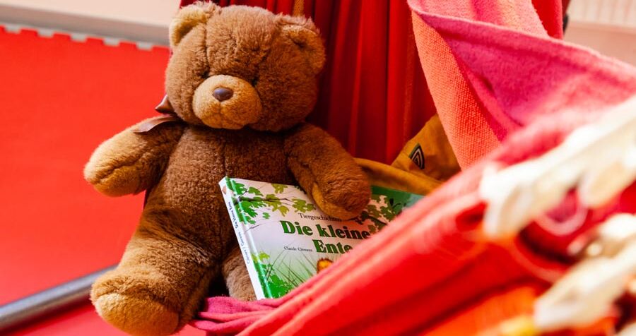Ein Stoffbär in einer Hängematte. Beim Bären liegen noch Kinderbücher. 