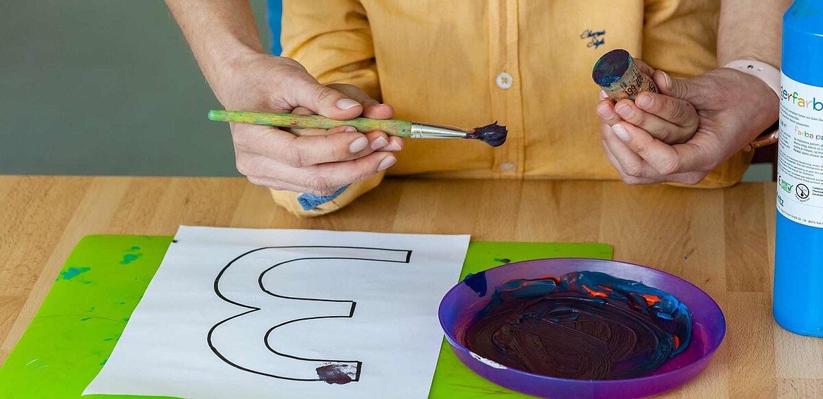 Ein Kind malt die Ziffer 3 auf ein Blatt Papier. 